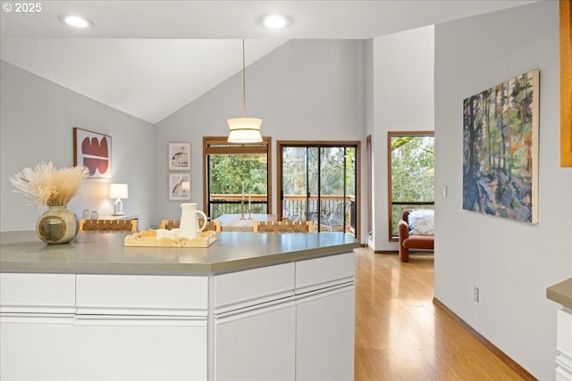 kitchen featuring white cabinetry, decorative light fixtures, light hardwood / wood-style flooring, and high vaulted ceiling