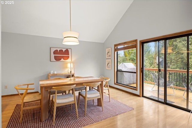 dining area with high vaulted ceiling and light hardwood / wood-style floors