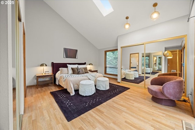 bedroom featuring hardwood / wood-style floors, a skylight, and high vaulted ceiling