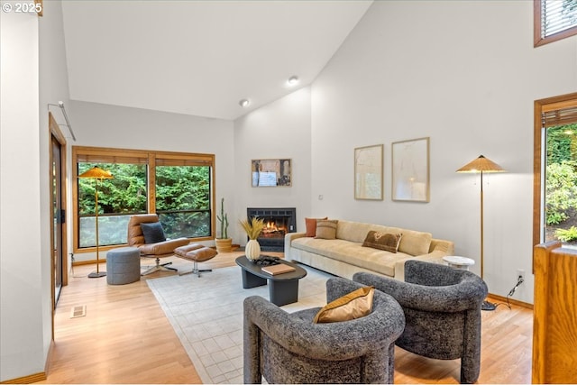 living room with light hardwood / wood-style floors and high vaulted ceiling