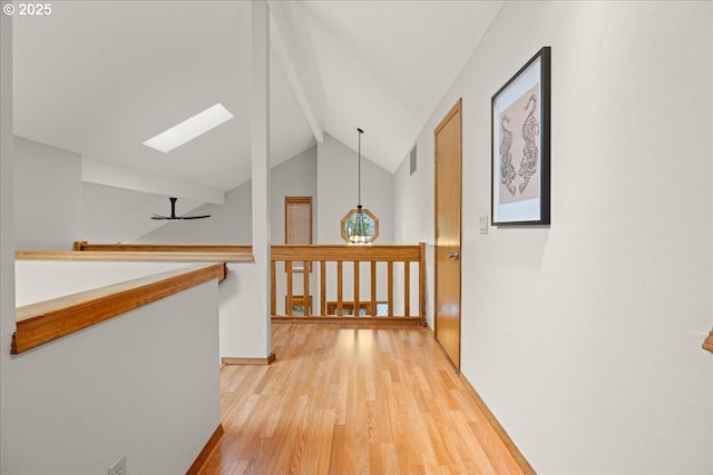 hallway featuring light hardwood / wood-style floors and vaulted ceiling with skylight