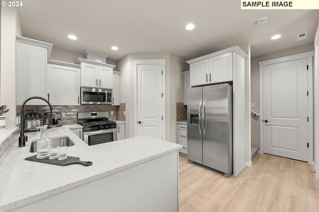 kitchen with appliances with stainless steel finishes, sink, decorative backsplash, and white cabinets