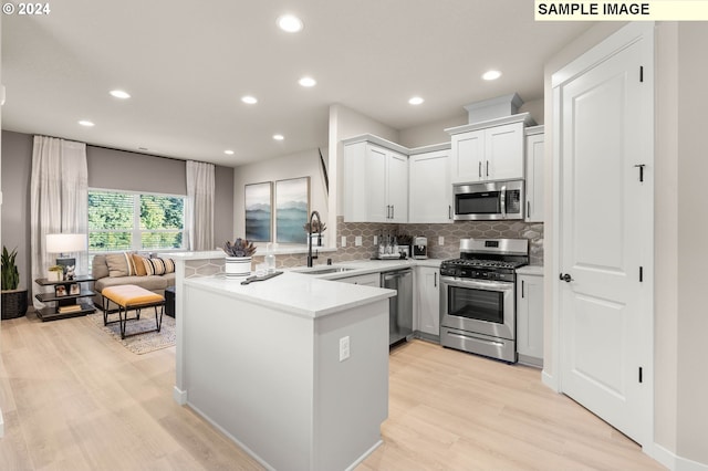 kitchen with white cabinetry, sink, kitchen peninsula, stainless steel appliances, and light hardwood / wood-style flooring