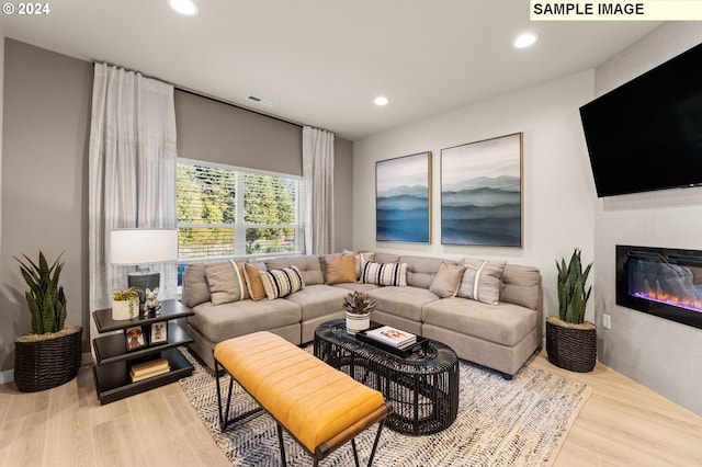 living room with a tiled fireplace and hardwood / wood-style flooring