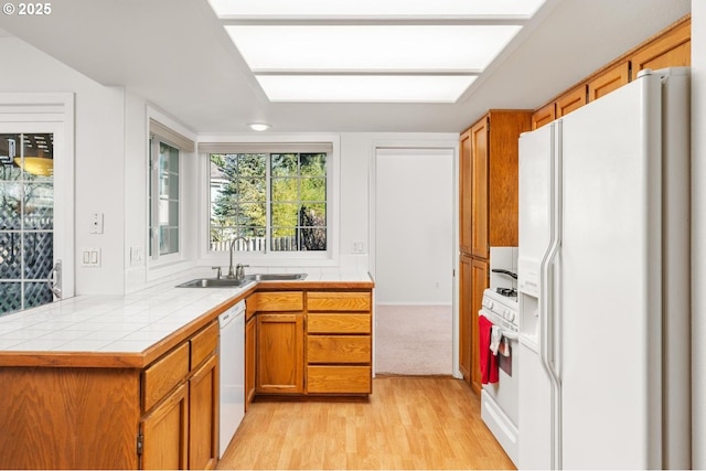 kitchen featuring sink, tile counters, light hardwood / wood-style floors, kitchen peninsula, and white appliances