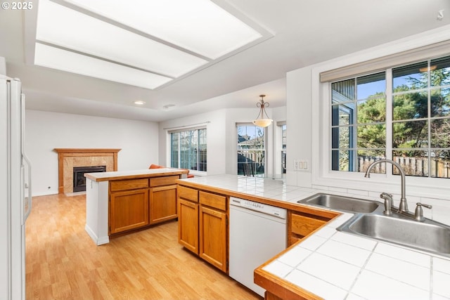 kitchen with sink, white appliances, tile counters, and a premium fireplace