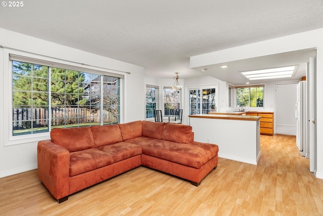 living room with a textured ceiling, light hardwood / wood-style flooring, and a wealth of natural light