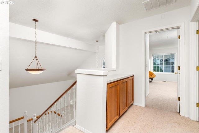 hall with light colored carpet and a textured ceiling