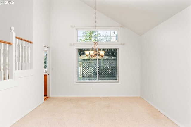 empty room with high vaulted ceiling, light colored carpet, and an inviting chandelier