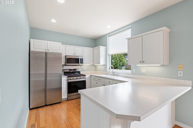 7408 SW Capitol Hwy, Portland, OR 97219 - kitchen with appliances with stainless steel finishes, a peninsula, white cabinets, light countertops, and recessed lighting