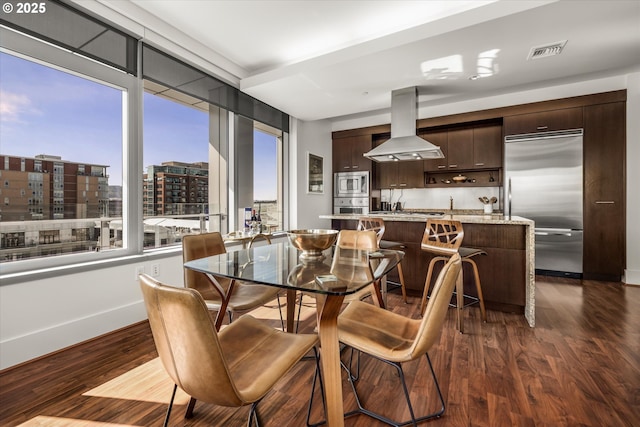 dining room with baseboards, a city view, dark wood finished floors, and visible vents