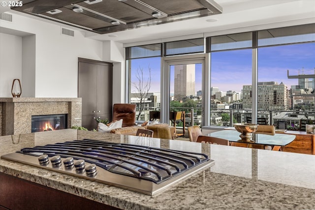 kitchen with floor to ceiling windows, visible vents, a high end fireplace, stainless steel gas cooktop, and a city view