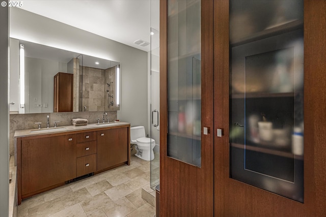 bathroom with double vanity, toilet, visible vents, and a sink