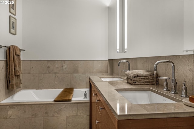 bathroom with double vanity, tiled bath, wainscoting, and a sink