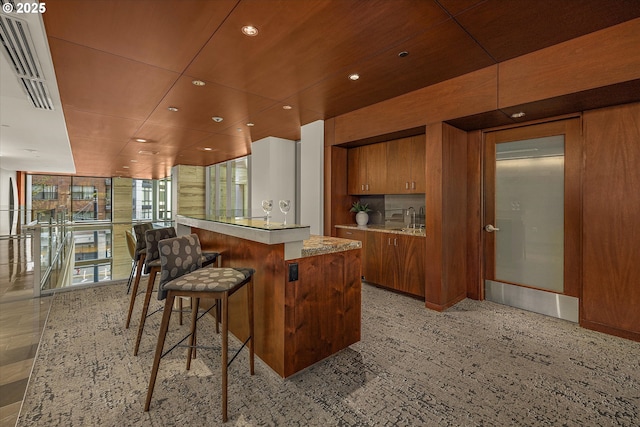 kitchen featuring a sink, light countertops, brown cabinetry, recessed lighting, and a kitchen island