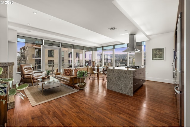 living room with dark wood-style flooring, baseboards, visible vents, and expansive windows