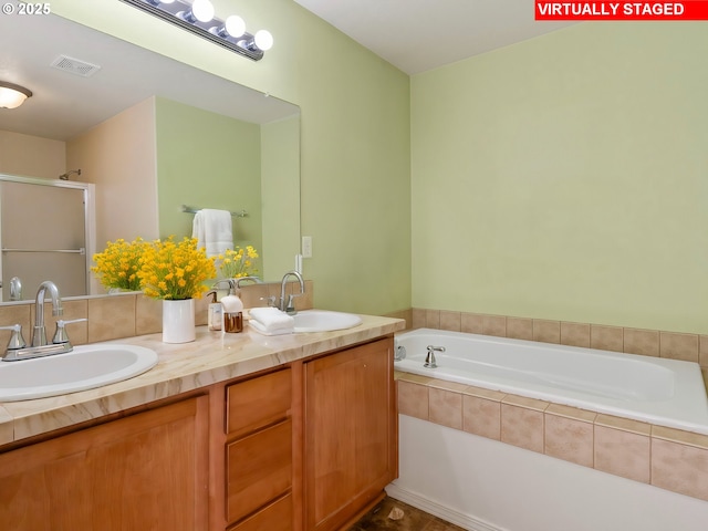 bathroom featuring vanity and tiled tub