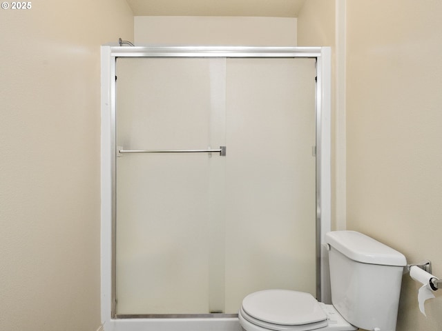 bathroom featuring a shower with shower door and toilet