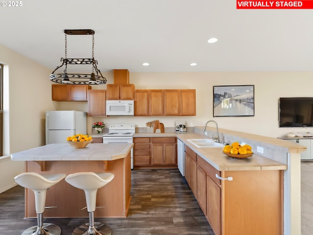 kitchen with sink, white appliances, a kitchen bar, and a kitchen island