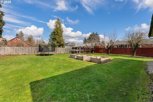 view of yard featuring a garden, a trampoline, and a fenced backyard