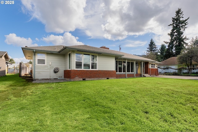 rear view of property with a yard, brick siding, and fence