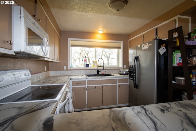 kitchen with white appliances, a textured ceiling, and a sink