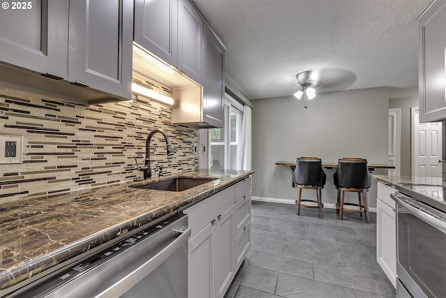 8396 SW Mohawk St, Tualatin, OR 97062 - kitchen with stainless steel appliances, decorative backsplash, dark stone counters, and ceiling fan
