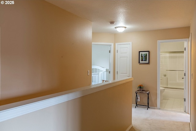 corridor featuring a textured ceiling, baseboards, and light colored carpet