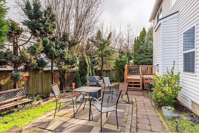 view of patio featuring outdoor dining area, a wooden deck, and a fenced backyard