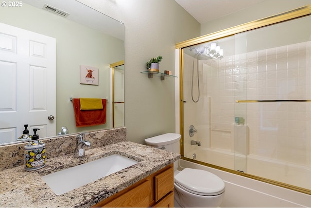 bathroom featuring visible vents, shower / bath combination with glass door, vanity, and toilet