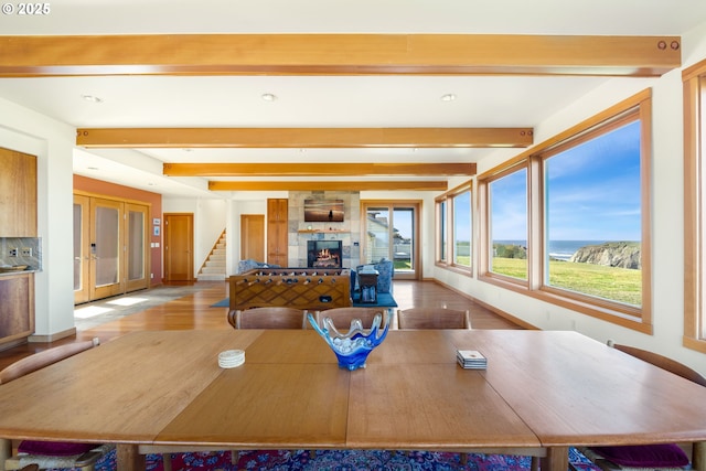 dining room featuring french doors, wood finished floors, beam ceiling, a fireplace, and stairway