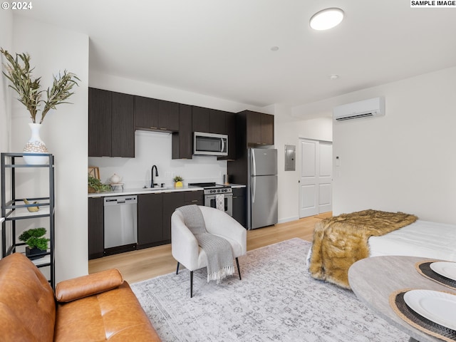 kitchen featuring dark brown cabinetry, sink, an AC wall unit, appliances with stainless steel finishes, and light wood-type flooring