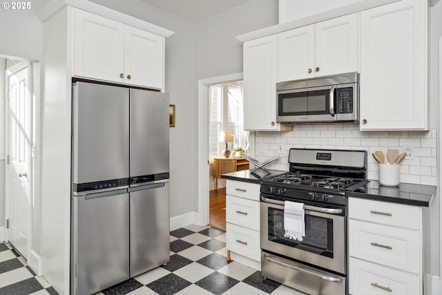 5106 N Bowdoin St, Portland, OR 97203 - kitchen with stainless steel appliances, dark floors, dark countertops, backsplash, and white cabinetry