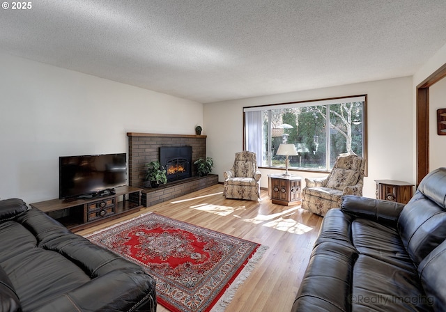 living room featuring a fireplace, a textured ceiling, and wood finished floors