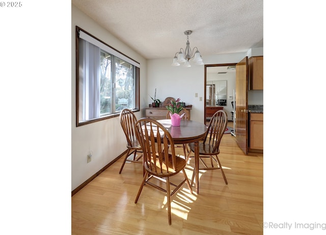 dining area with a notable chandelier, baseboards, light wood-style floors, and a textured ceiling