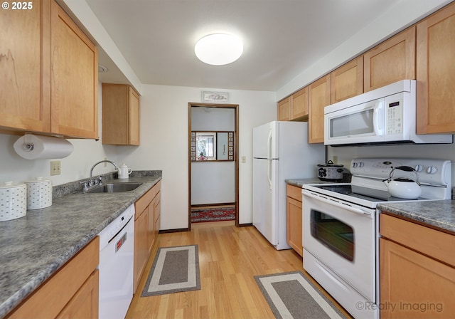 kitchen featuring dark countertops, light brown cabinetry, light wood-type flooring, white appliances, and a sink