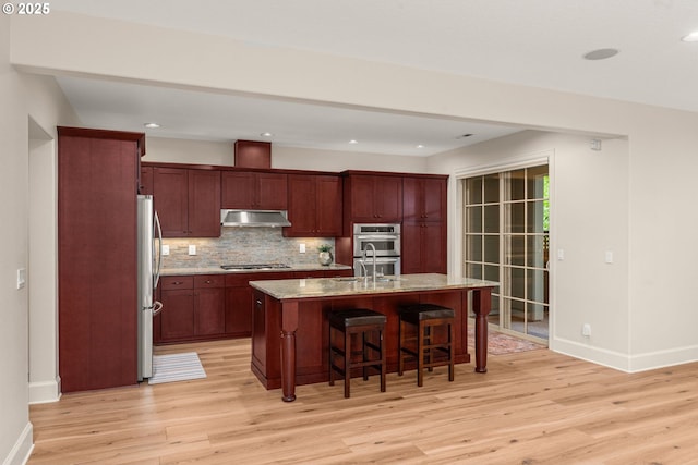 4661 Trillium, Woods, Lake Oswego, OR 97035 - kitchen with under cabinet range hood, stainless steel appliances, light wood finished floors, a kitchen breakfast bar, and recessed lighting