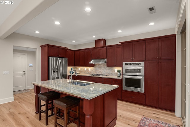 4661 Trillium, Woods, Lake Oswego, OR 97035 - kitchen with stainless steel appliances, under cabinet range hood, reddish brown cabinets, light wood-style flooring, and recessed lighting