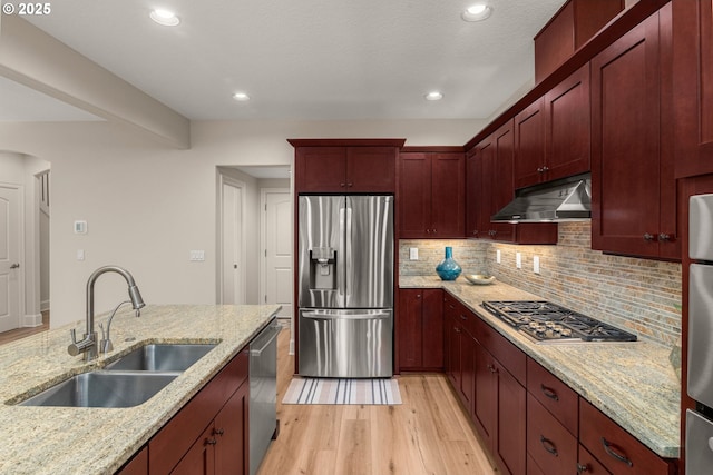 4661 Trillium, Woods, Lake Oswego, OR 97035 - kitchen featuring stainless steel appliances, under cabinet range hood, light wood finished floors, reddish brown cabinets, and tasteful backsplash