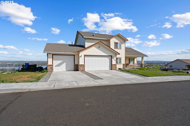 175 Truman Dr, Umatilla, OR 97882 - view of front facade featuring a water view, an attached garage, stone siding, fence, and driveway