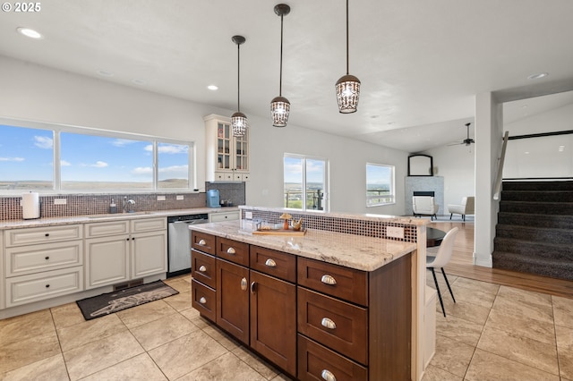 175 Truman Dr, Umatilla, OR 97882 - kitchen with stainless steel dishwasher, glass insert cabinets, tasteful backsplash, a breakfast bar area, and plenty of natural light