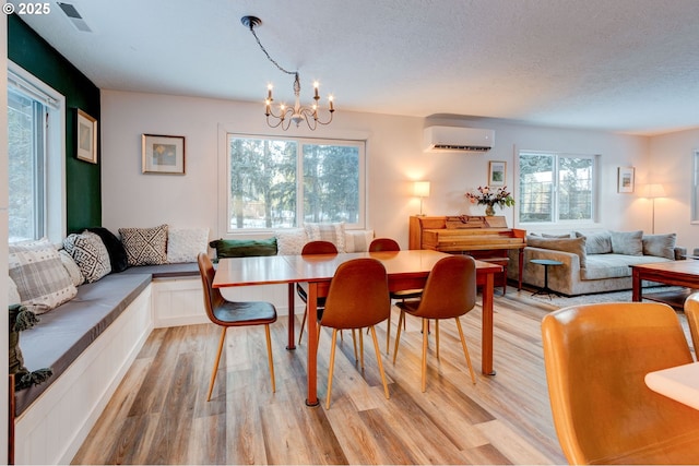 24492 SE Three Cedars St, Damascus, OR 97089 - dining area featuring light wood-type flooring, a wall mounted air conditioner, a chandelier, and a textured ceiling