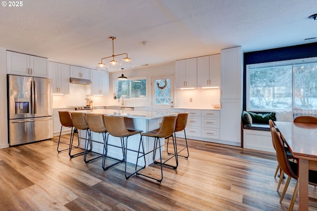 24492 SE Three Cedars St, Damascus, OR 97089 - kitchen featuring stainless steel fridge, under cabinet range hood, white cabinetry, backsplash, and a textured ceiling