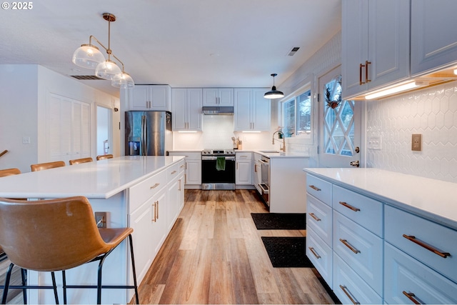 24492 SE Three Cedars St, Damascus, OR 97089 - kitchen with appliances with stainless steel finishes, light wood-style floors, under cabinet range hood, and light countertops