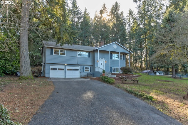 24492 SE Three Cedars St, Damascus, OR 97089 - bi-level home featuring asphalt driveway, a chimney, a garage, and view of scattered trees