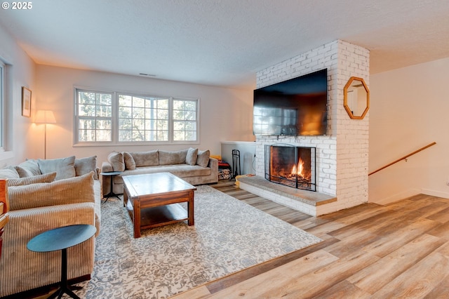 24492 SE Three Cedars St, Damascus, OR 97089 - living room with wood finished floors, a brick fireplace, and a textured ceiling