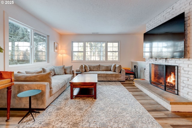 24492 SE Three Cedars St, Damascus, OR 97089 - living area with wood finished floors, a textured ceiling, and a brick fireplace