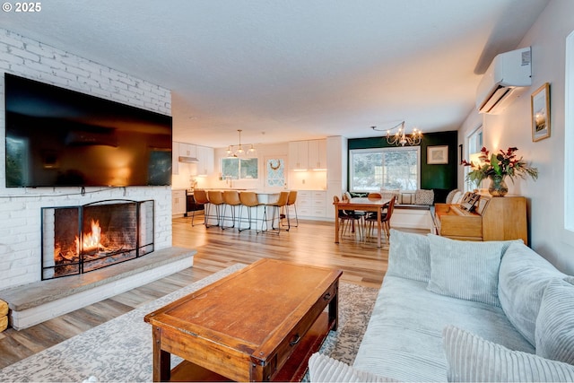 24492 SE Three Cedars St, Damascus, OR 97089 - living area with a wall mounted air conditioner, a chandelier, light wood-style floors, and a brick fireplace