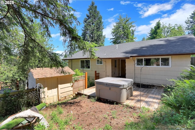 8157 S A St, Springfield, OR 97478 - rear view of property featuring a hot tub, a deck, a storage unit, and roof with shingles