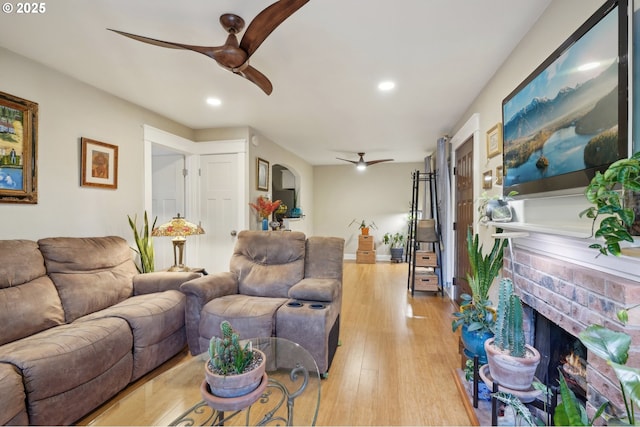 living room featuring a fireplace, light hardwood / wood-style flooring, and ceiling fan